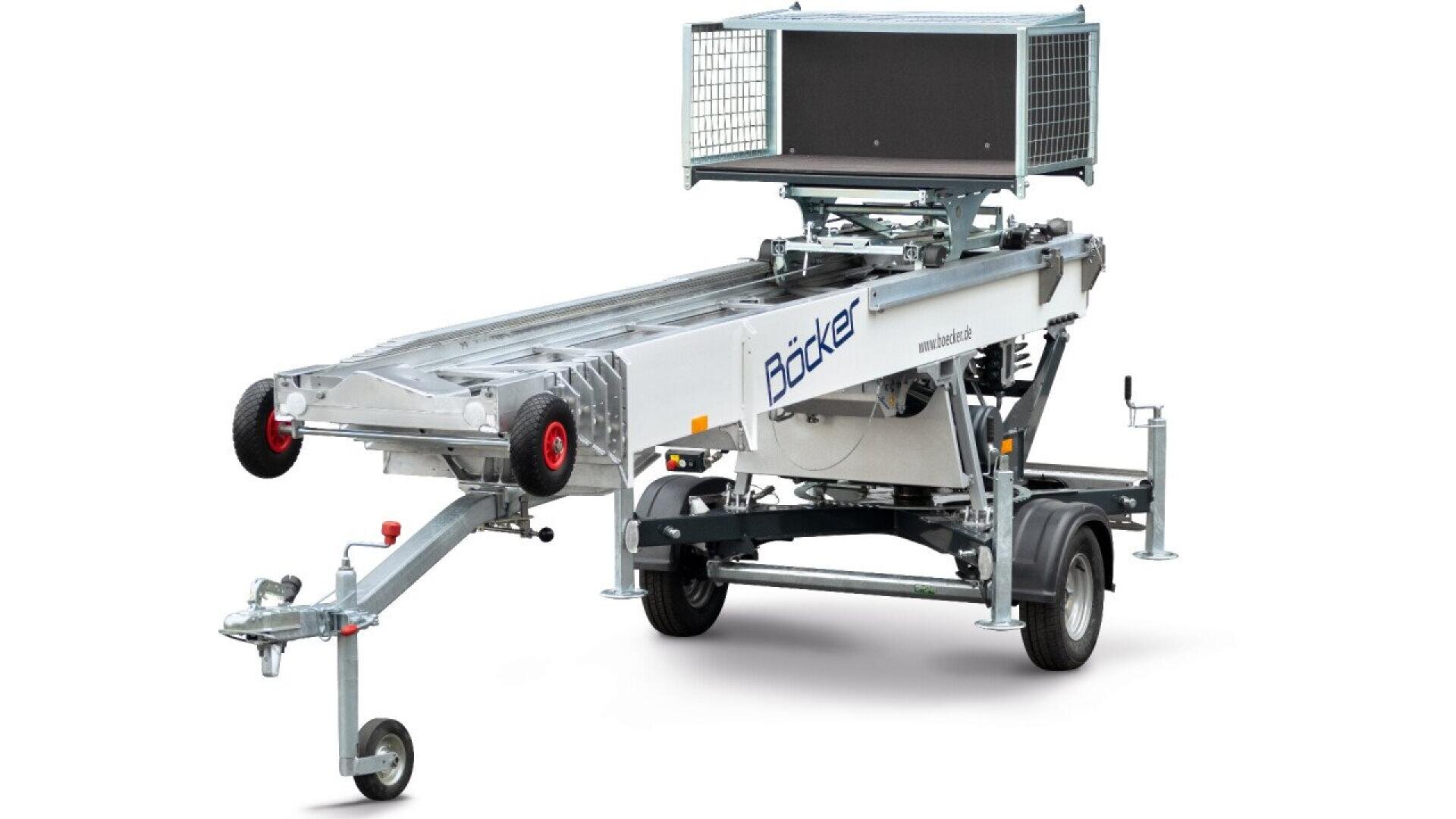 A silver, wheeled trailer with a long, extendable platform and a cage-like metal structure on top, designed for transporting materials. The trailer has red-rimmed wheels and a hitch for towing.