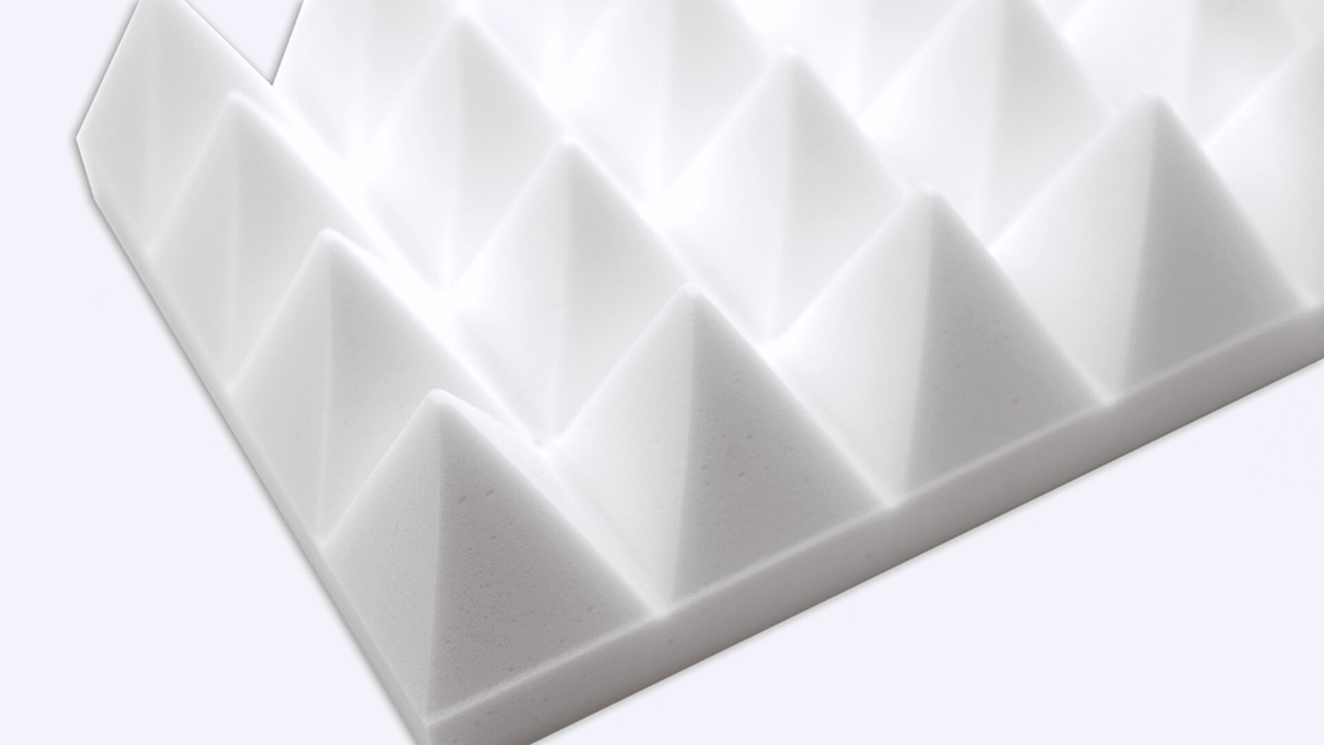 Eine Nahaufnahme einer weißen Schaumstoffplatte mit einem Gitter aus pyramidenförmigen Spitzen, die häufig zur Schalldämmung oder akustischen Behandlung verwendet wird, vor einem schlichten Hintergrund.