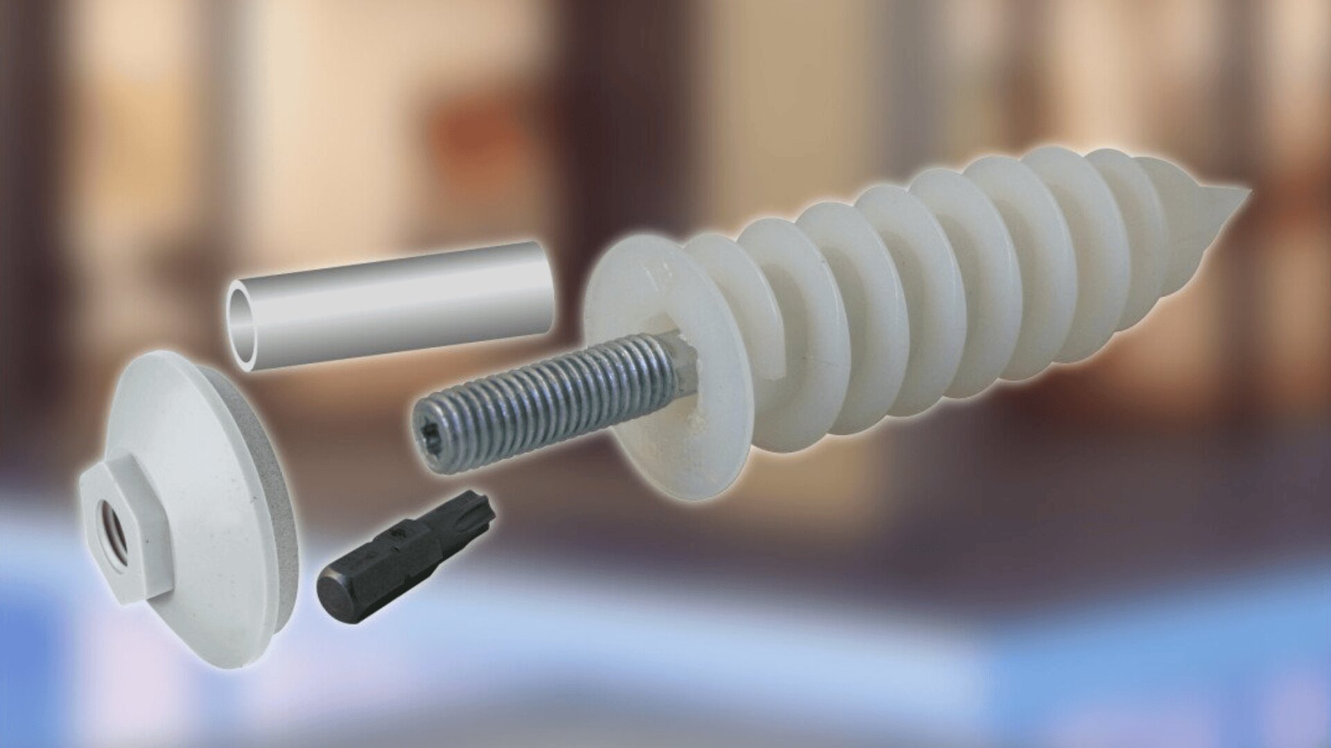 A close-up of a plastic wall anchor system, including a white spiral anchor, a metal insert, a plastic spacer, a gray screwdriver bit, and a white cap, displayed against a blurred indoor background.