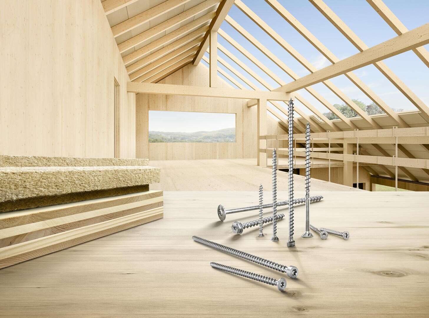In einem hellen, unfertigen Holzgebäude mit freiliegenden Balken und großen Fenstern, die den Blick nach draußen freigeben, sind mehrere Metallschrauben und Schichten von Baumaterialien auf einer Holzoberfläche ausgestellt.