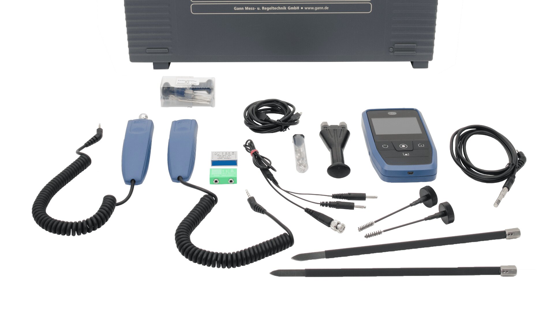 A set of electronic measuring instruments and accessories, including probes, cables, and a handheld digital device, arranged neatly on a white background with a black carrying case in the back.