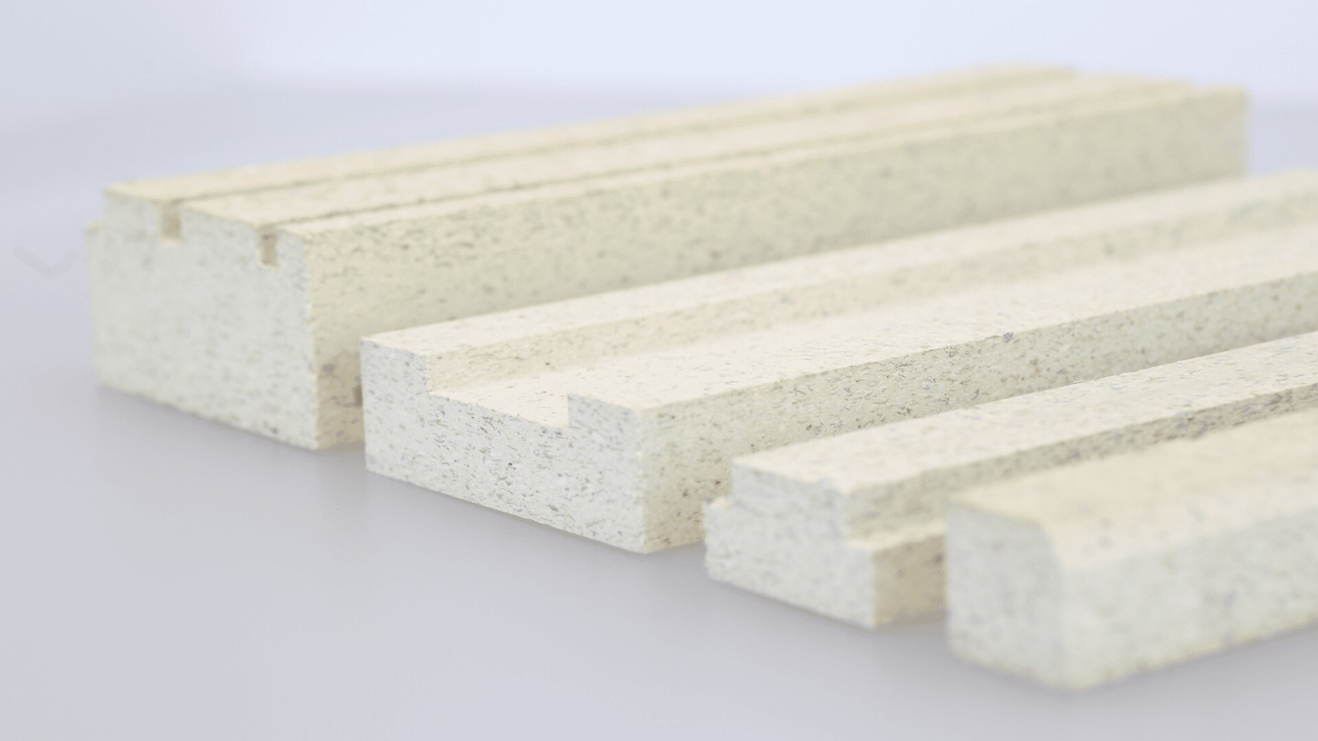 Four rectangular beige foam blocks of varying thickness and groove patterns are arranged on a smooth, light surface, shown in a close-up with a soft focus background.