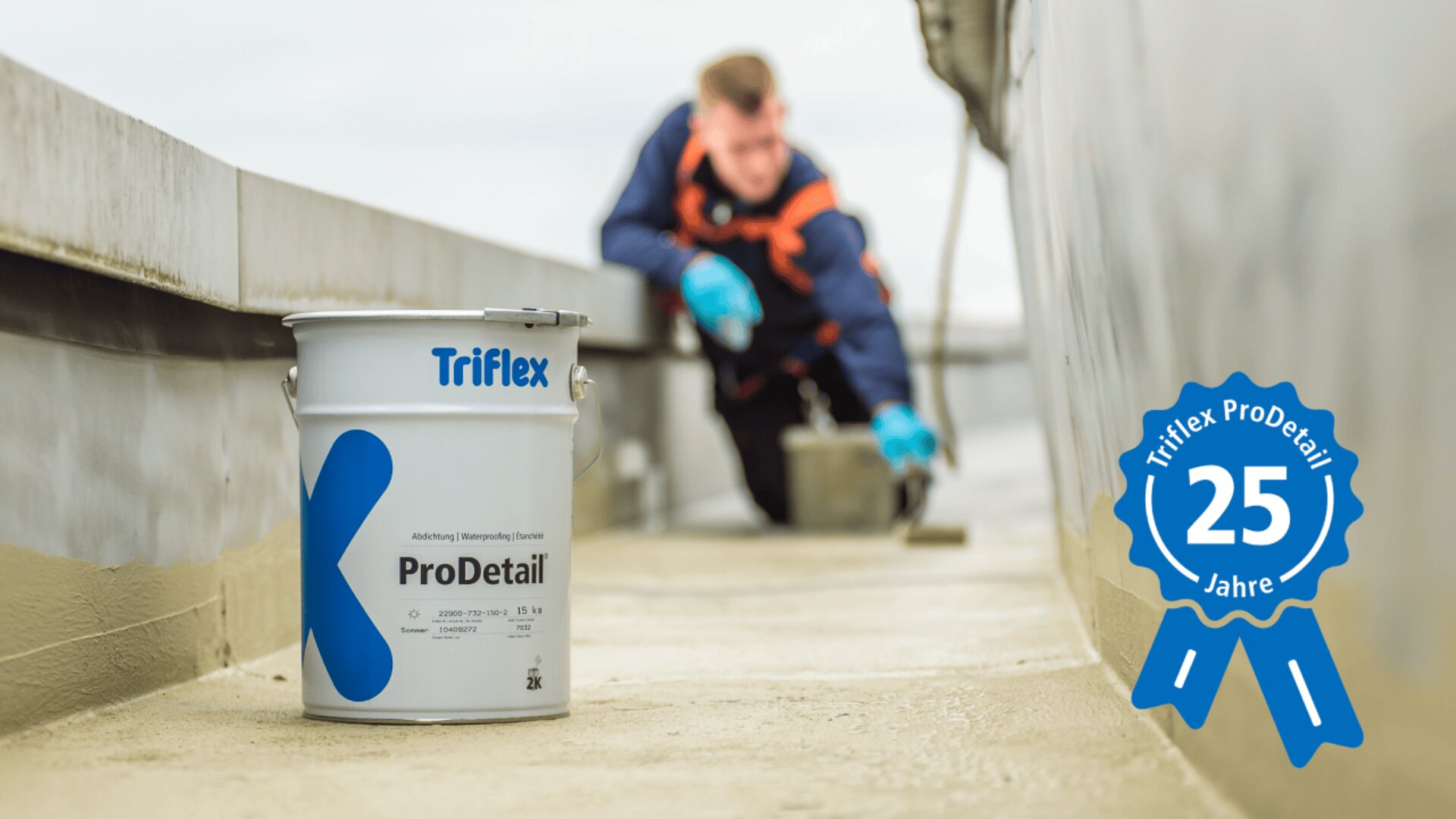 Auf einem Flachdach steht ein Container mit der Aufschrift „Triflex ProDetail“, während im Hintergrund ein Arbeiter Material auf die Oberfläche aufträgt. Auf einem blauen Schild rechts steht „Triflex ProDetail 25 Jahre“.