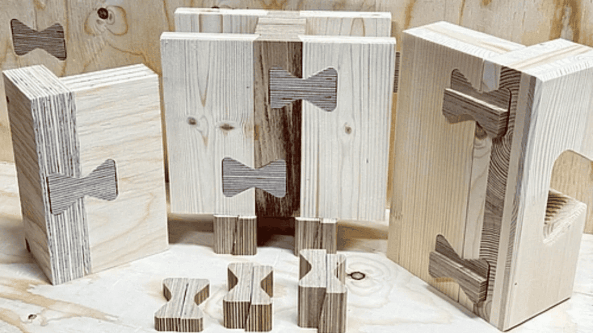 Several pieces of light-colored wood with visible dark butterfly or bowtie-shaped joint inlays, displayed upright and flat on a wooden surface. Some separate bowtie inlays are placed in front.