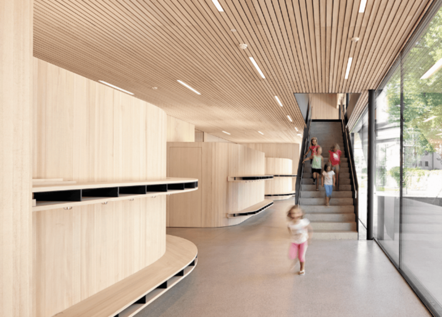 Modernes Interieur mit hellen Holzwänden und -decken, eingebauten Regalen, großen Fenstern und einer Treppe. Erwachsene und Kinder gehen spazieren, wobei ein Kind in Bewegungsunschärfe erscheint, was eine lebendige, offene Atmosphäre schafft.
