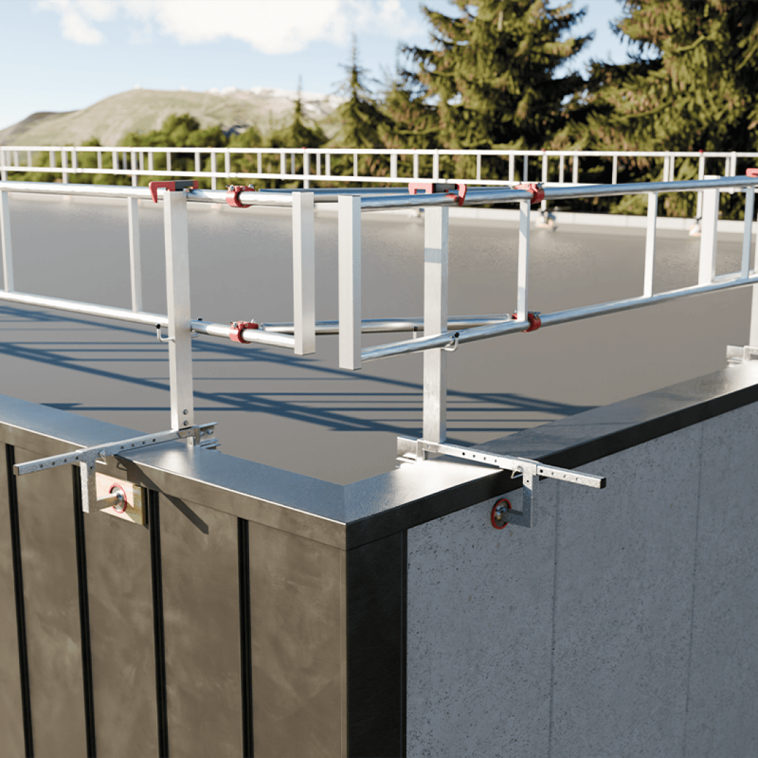 A metal roof railing system with safety rails and brackets installed along the edge of a flat building roof, with trees and mountains visible in the background.