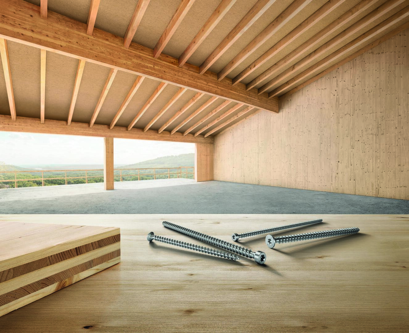 Ein paar große Metallschrauben liegen auf einer Holzoberfläche in einem geräumigen Raum im Bau, der über freiliegende Holzbalken, Sperrholzwände und einen freien Blick auf die grünen Hügel draußen verfügt.