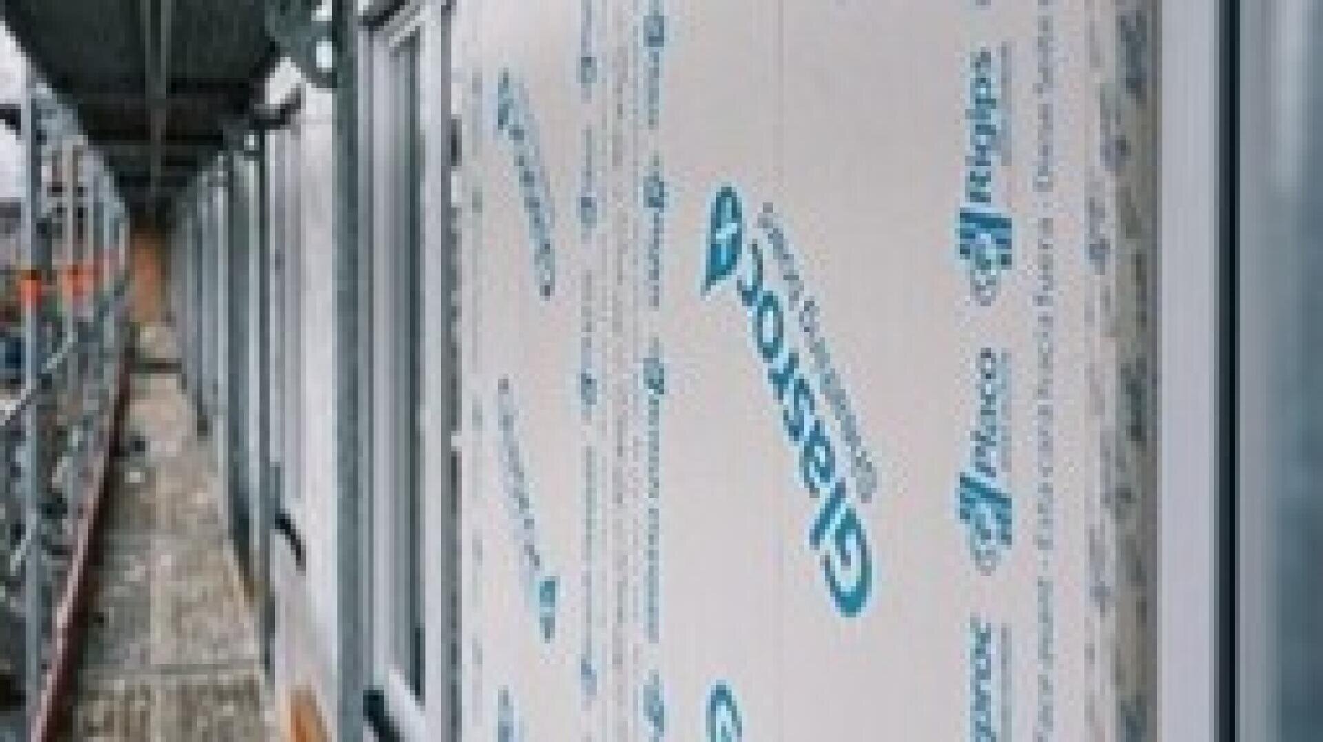 Nahaufnahme eines im Bau befindlichen Gebäudes mit einer Wand, die mit Glasroc-Platten verkleidet ist, und einem Gerüst, das entlang der Konstruktion verläuft.