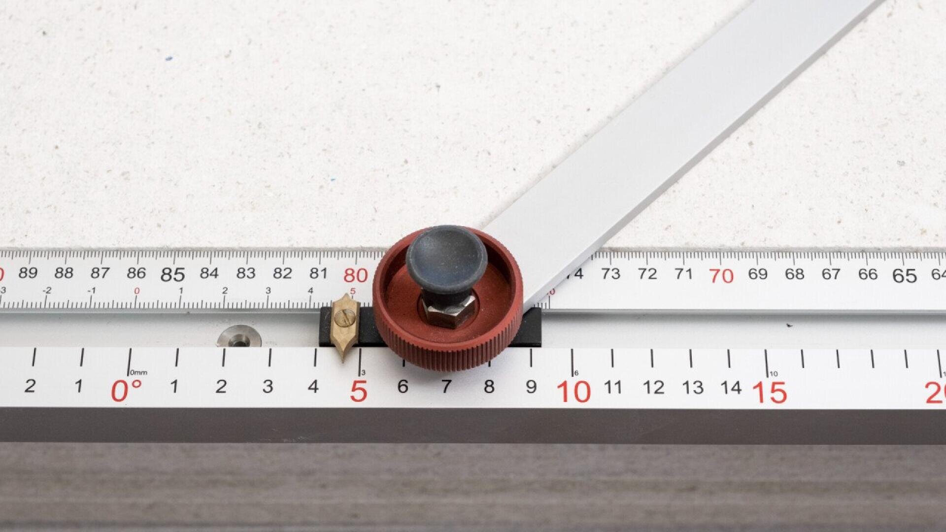 Eine Nahaufnahme eines Metalllineals und Messwerkzeugs mit einem rot-schwarzen Einstellknopf, der Messungen in Zentimetern und Grad auf einem weißen Hintergrund anzeigt.