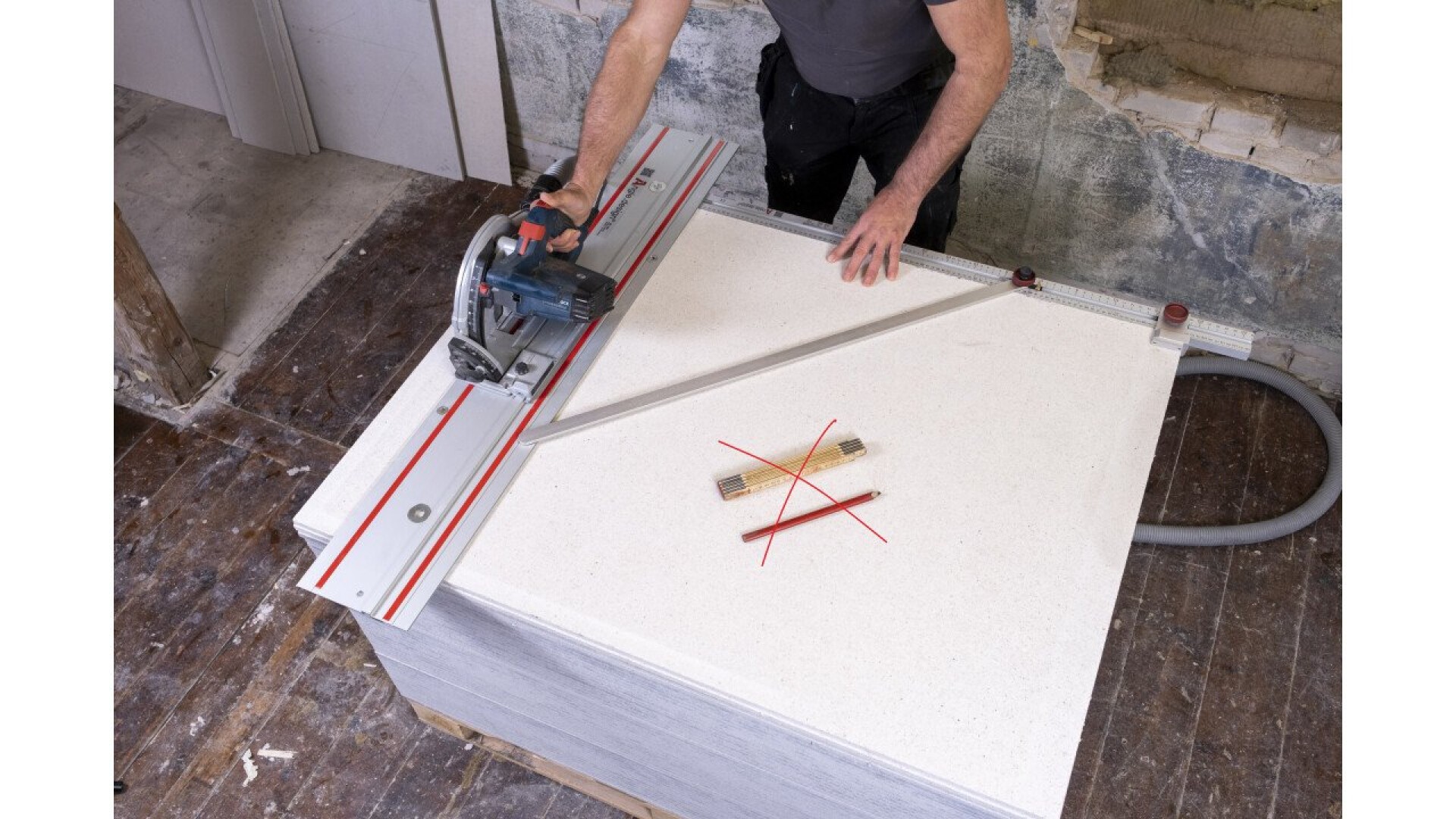 Eine Person schneidet mit einer Kreissäge mit Führungsschiene eine große Materialplatte. Auf der Platte sind Lineal und Bleistift mit einem roten X durchgestrichen, was bedeutet, dass sie nicht zum Messen oder Markieren verwendet werden dürfen.
