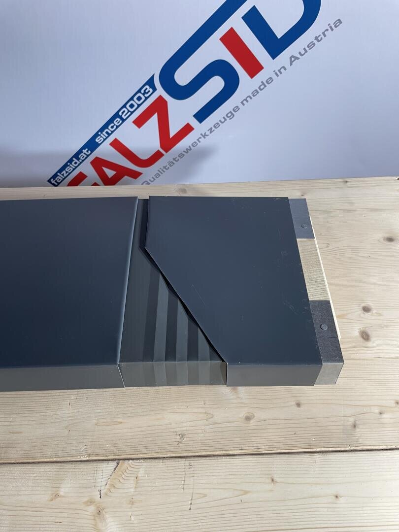 Eine Nahaufnahme eines Präzisionsmetallwerkzeugs mit geometrischen Rillen auf einer hellen Holzoberfläche vor einem Schild mit der Aufschrift „SALZSID“ und „Qualitätswerkzeuge made in Austria“.