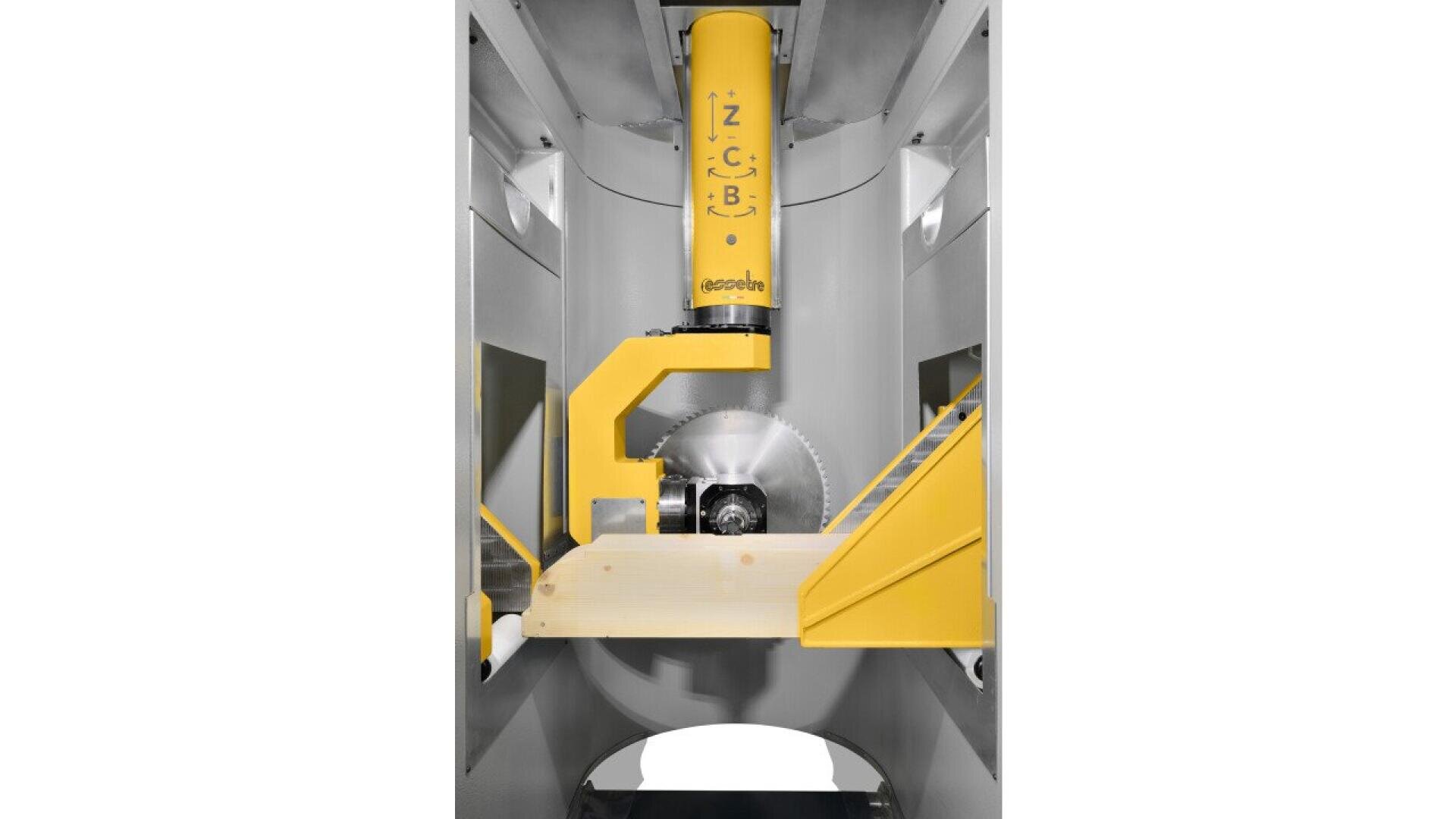A close-up of an industrial machine with a circular saw blade, yellow mechanical arm, and a wooden plank positioned below the blade inside a metallic enclosure.
