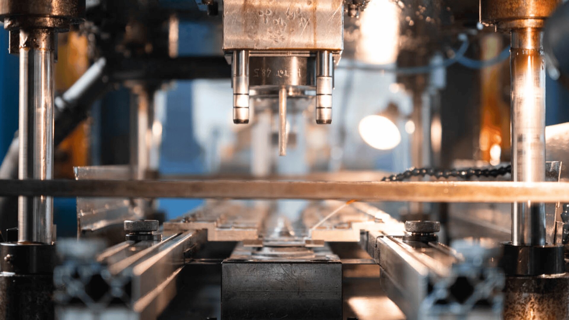 Close-up view of a CNC machine in operation, showing metal parts being precisely machined under a bright industrial light in a manufacturing environment.