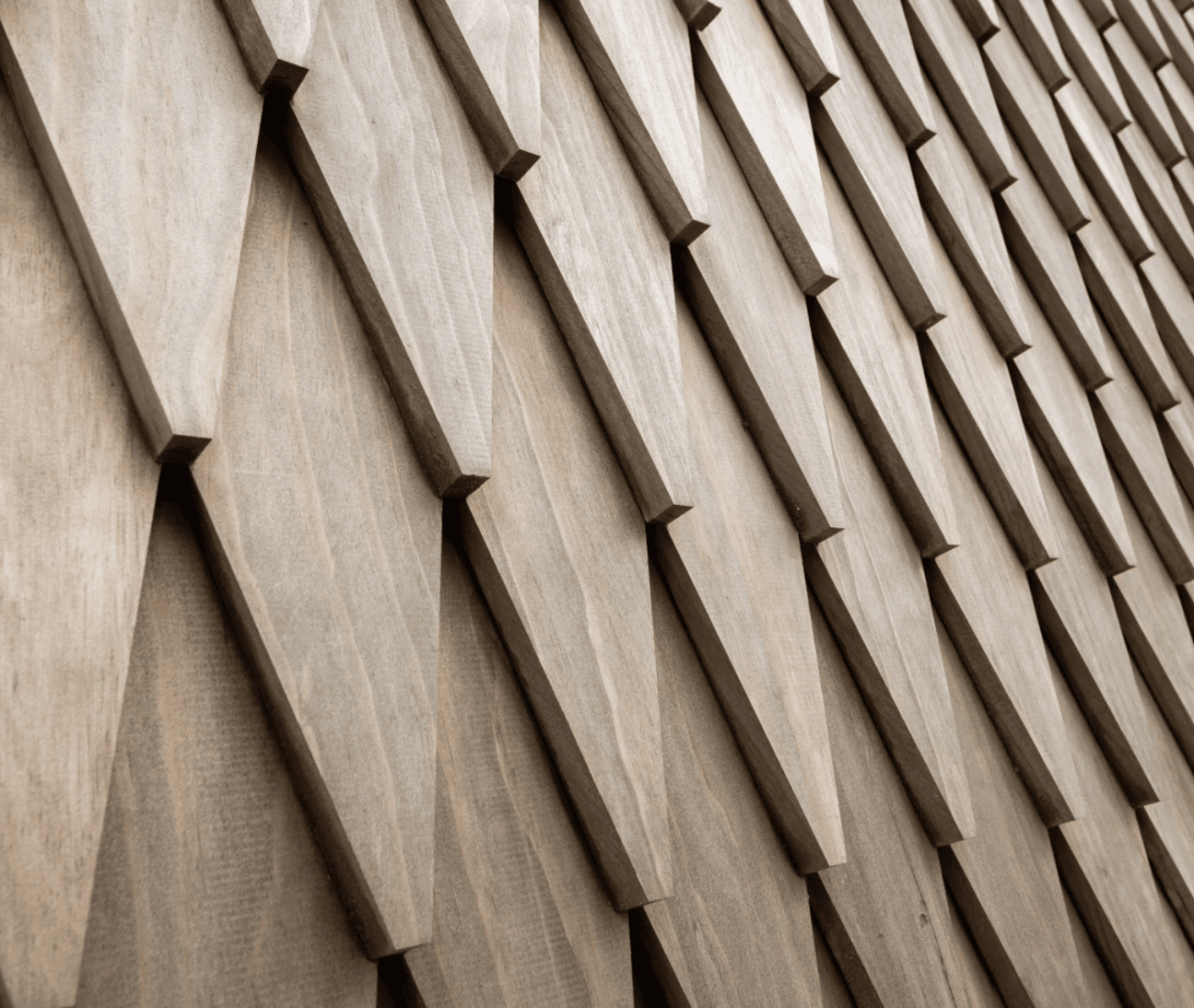 Close-up of a wall clad with overlapping, diamond-shaped wooden panels that create a structured, geometric pattern in different shades of brown.